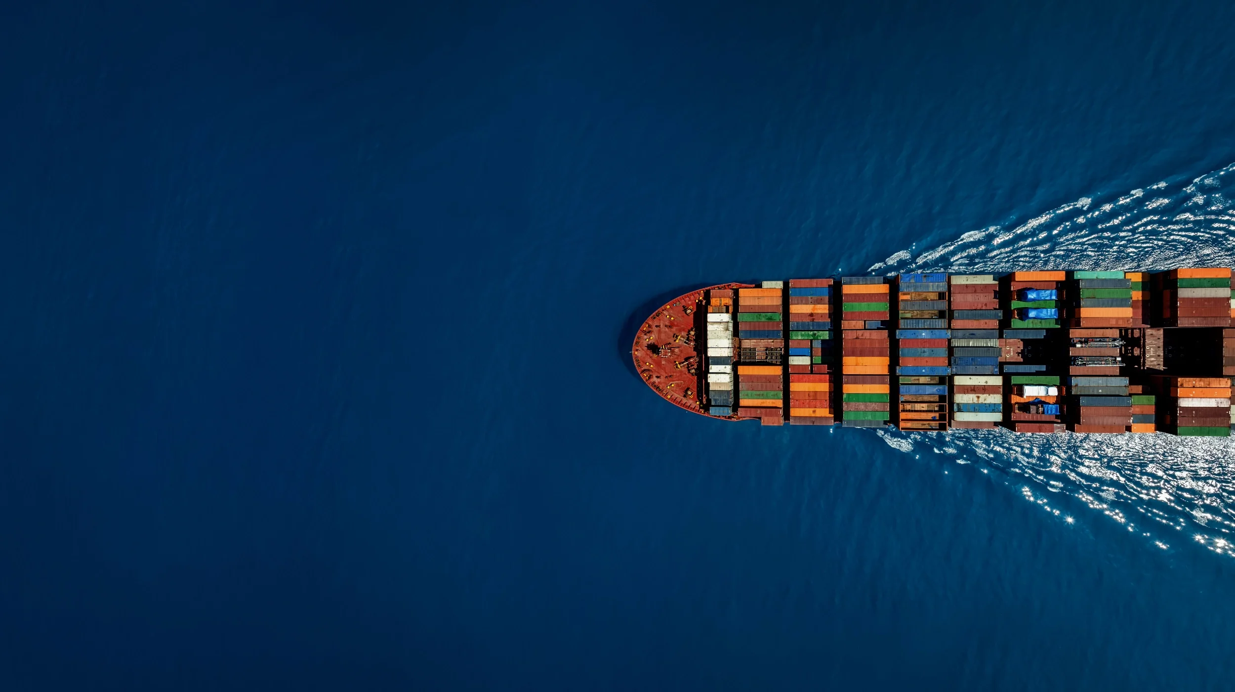 Vogelperspektive eines voll beladenen Containerschiffs auf dem Ozean, das für globale Lieferketten und professionelle Einkaufsberatung für den Mittelstand steht.