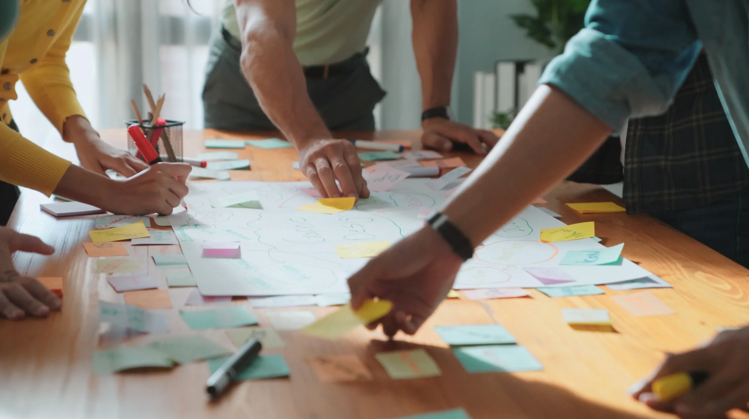 Nahaufnahme von Händen, die bei einem Workshop bunte Notizzettel auf einem Strategieplan anordnen, stellvertretend für die strukturierte Analyse und schrittweise Umsetzung eines effizienteren Einkaufs.