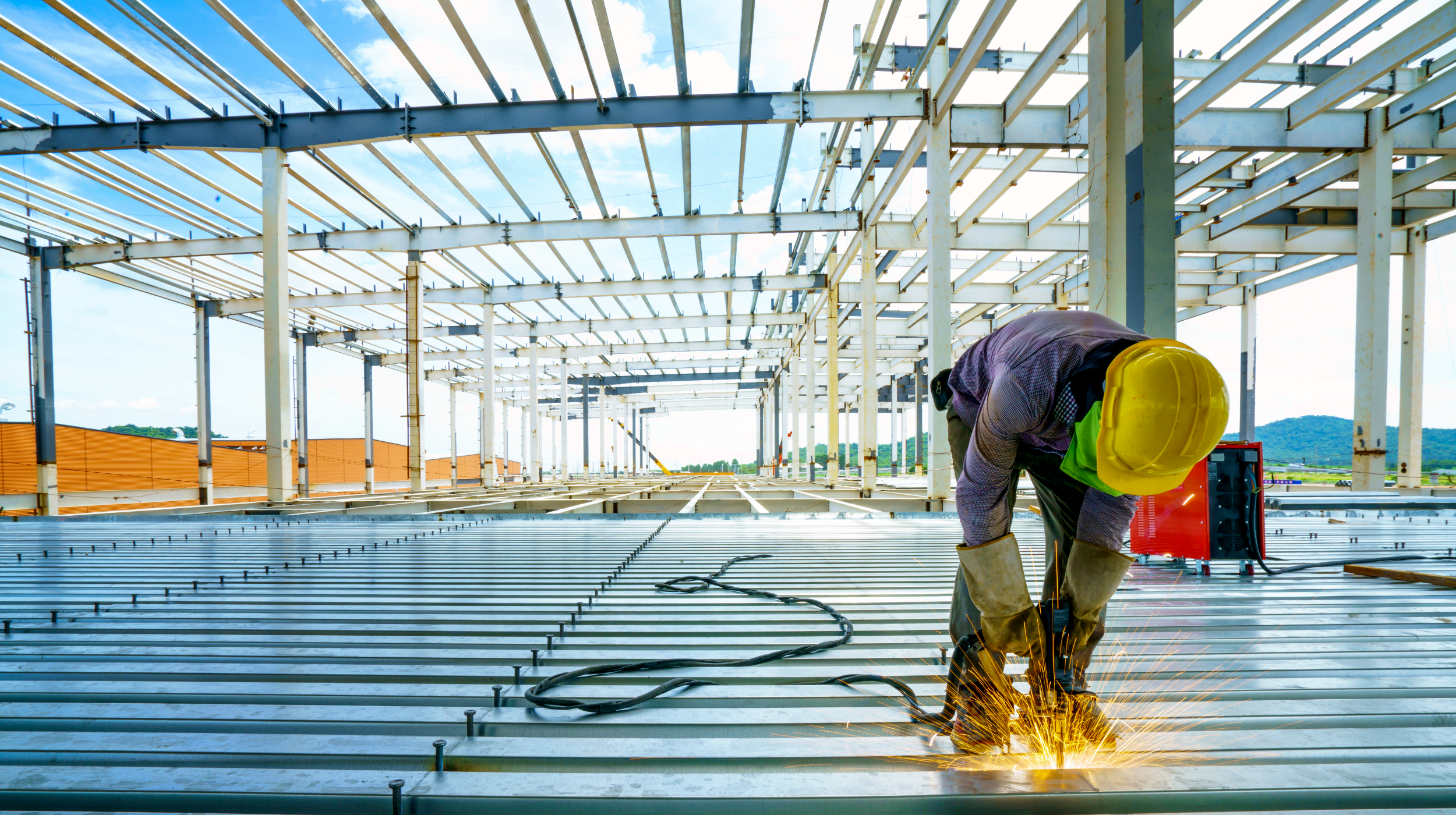 Ein Bauarbeiter beim Errichten einer massiven Stahlkonstruktion, was symbolisch für den Aufbau dauerhaft stabiler Strukturen und die Optimierung von Einkaufsprozessen steht.
