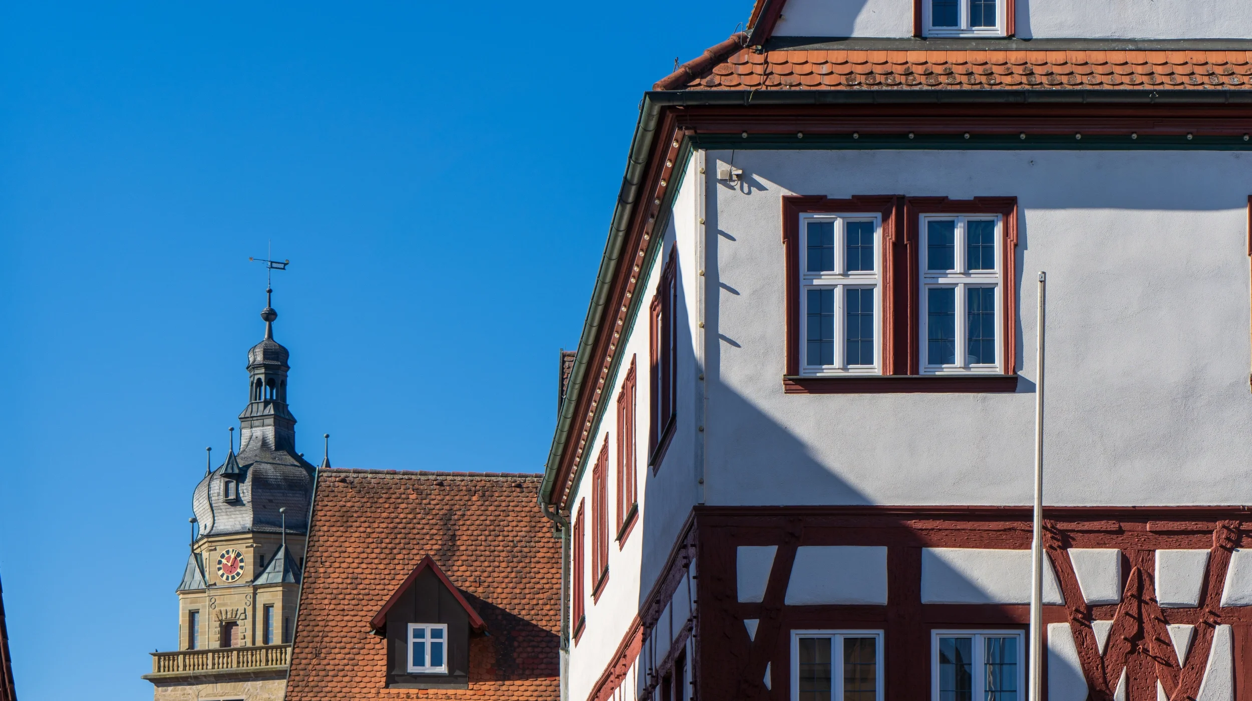 Historisches Fachwerkgebäude mit Ziegeldächern in Neuenstein, stellvertretend für unsere tiefe Verwurzelung im Mittelstand und 25 Jahre Erfahrung in der Einkaufsberatung.