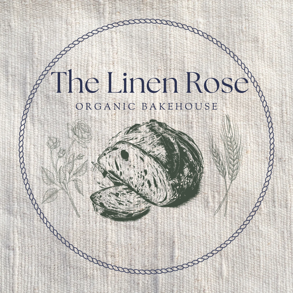 Label for The Linen Rose Organic Bakehouse with an illustration of nuts and wheat inside a circle, on a textured fabric background.
