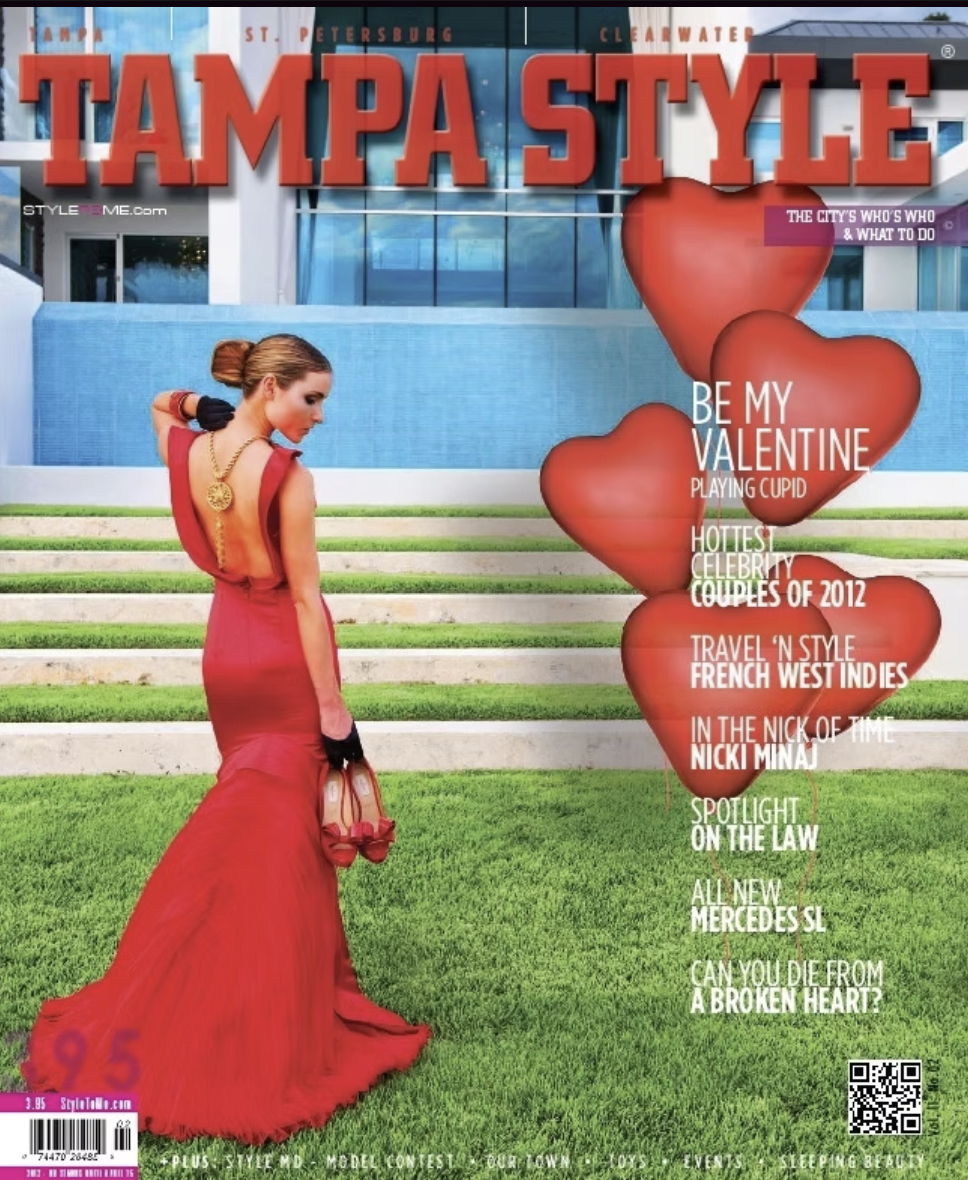 Cover of Tampa Style magazine featuring a woman in a long red gown holding red shoes, standing on steps in front of a modern building with a water feature; magazine includes headlines about Valentine's Day, celebrities, travel, and local events.
