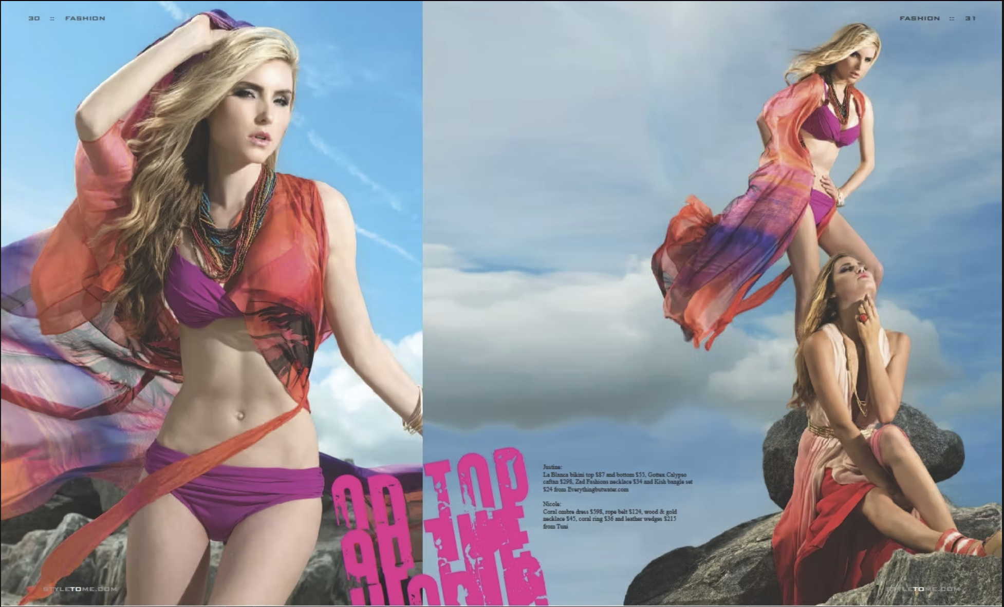 Two women dressed in colorful fashion poses outdoors against a blue sky with clouds. One woman stands on rocks wearing a purple swimsuit with a sheer orange and purple cover-up, accessorized with jewelry. The other woman sits on rocks wearing a pink 