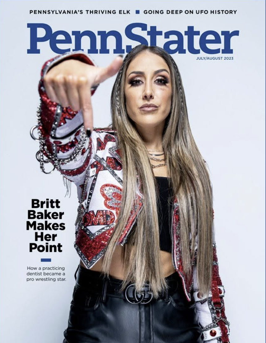Cover of Penn Stater magazine July/August 2023 featuring a woman with long blonde hair in a red and white jacket, pointing at the camera. The headline reads, "Britt Baker Makes Her Point" with a subheading about her journey from practicing dentist to