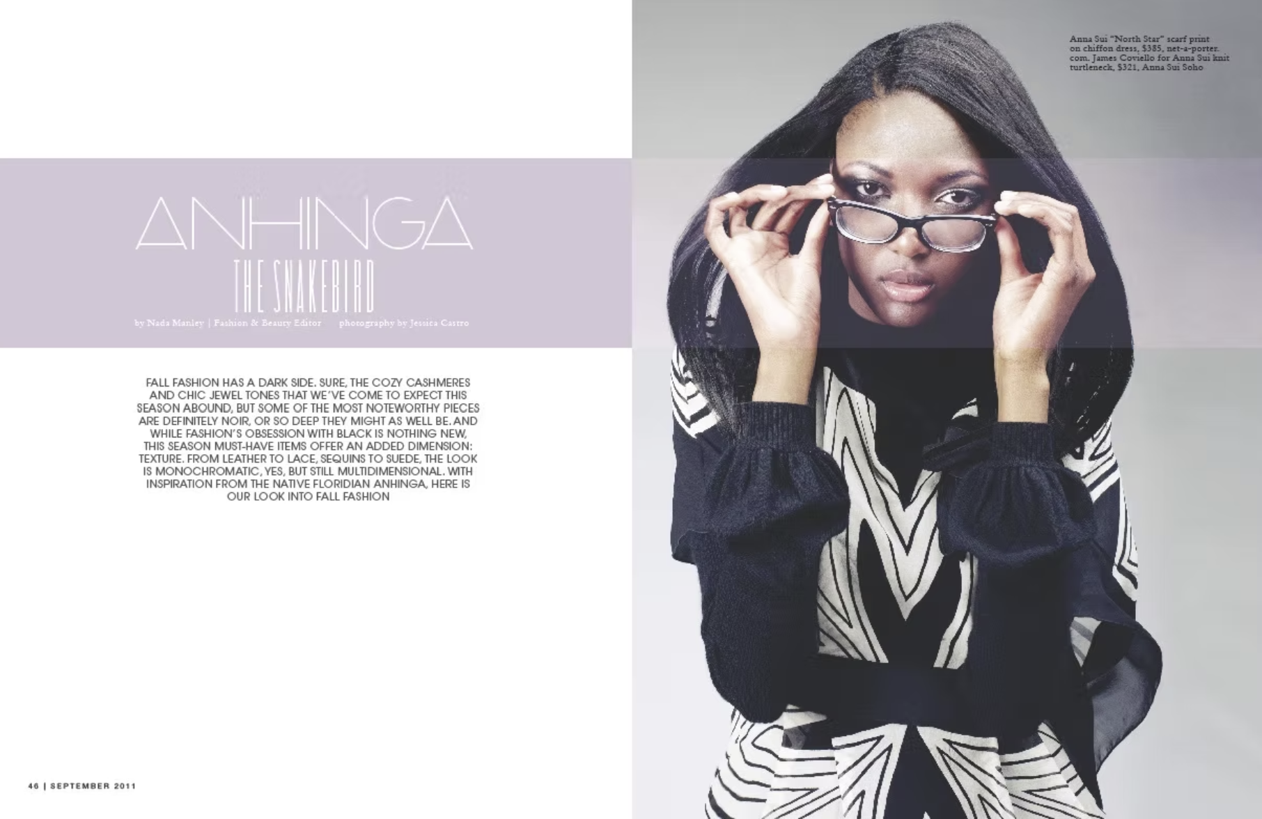 A woman with long black hair and glasses, wearing a black and white patterned outfit, holds her glasses as she looks at the camera.