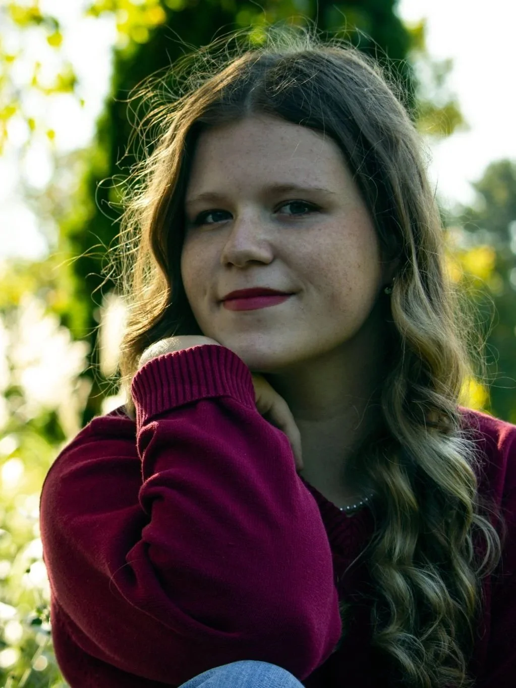 This is a headshot of me outside by trees.