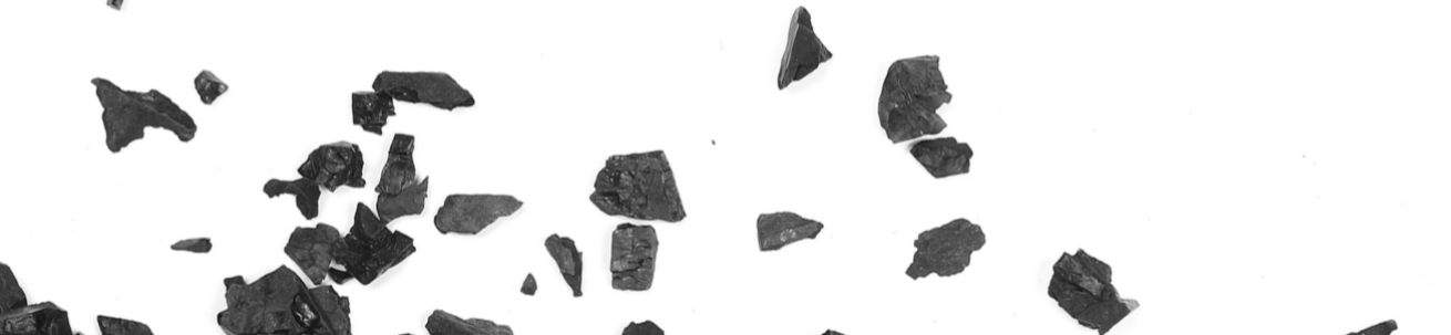 Small black charcoal pieces scattered on white background.