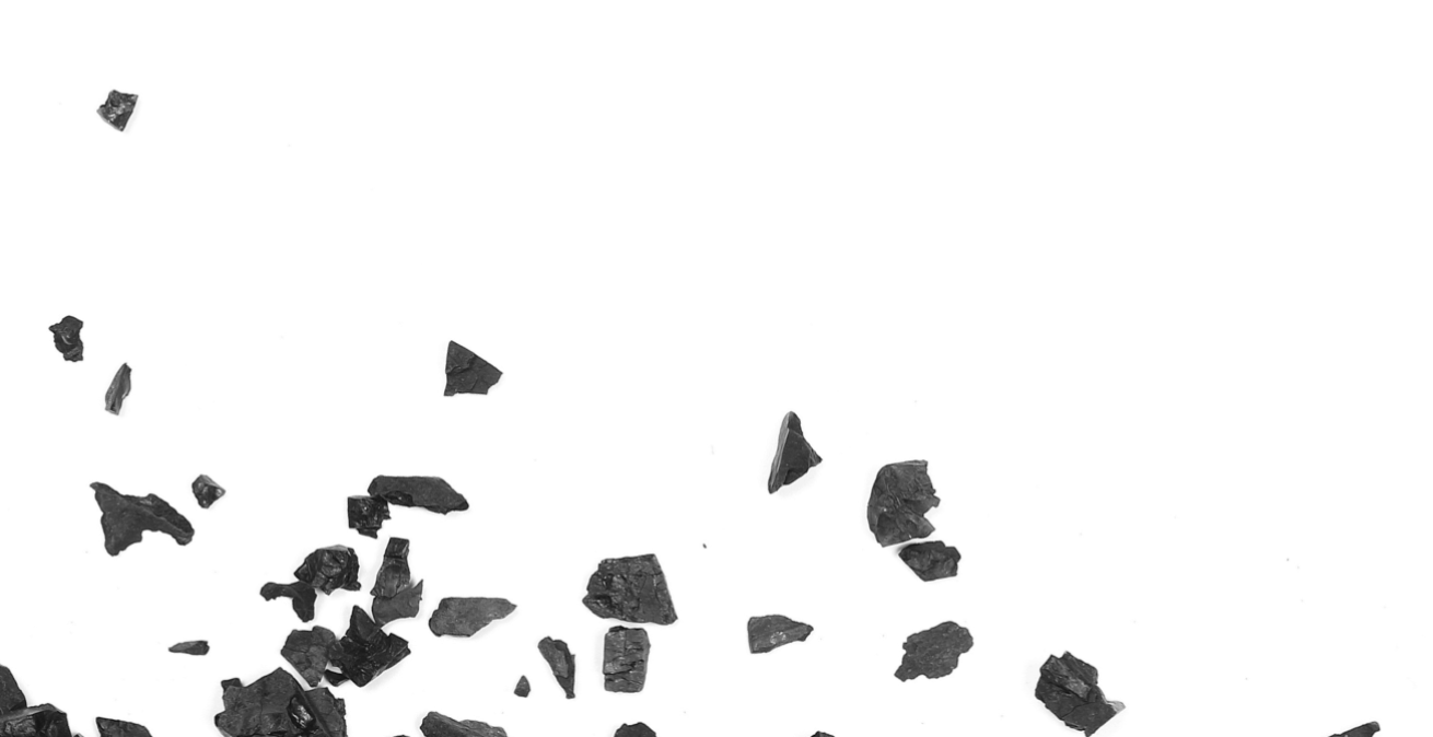 Black crushed charcoal pieces scattered on a white background.
