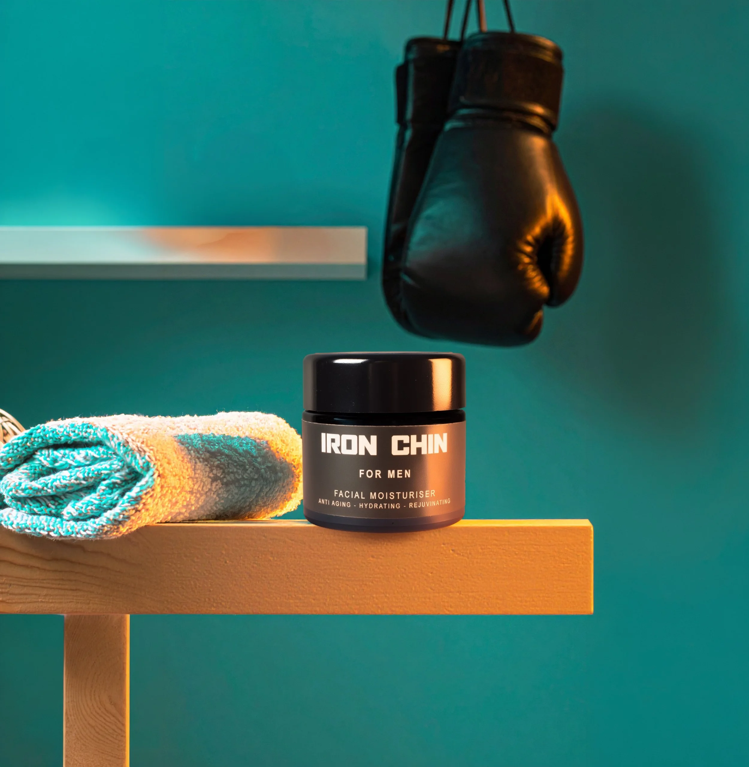 A pair of boxing gloves hanging on the wall, next to a bottle of facial moisturizer labeled 'Iron Chin' with the tagline 'For Men'.