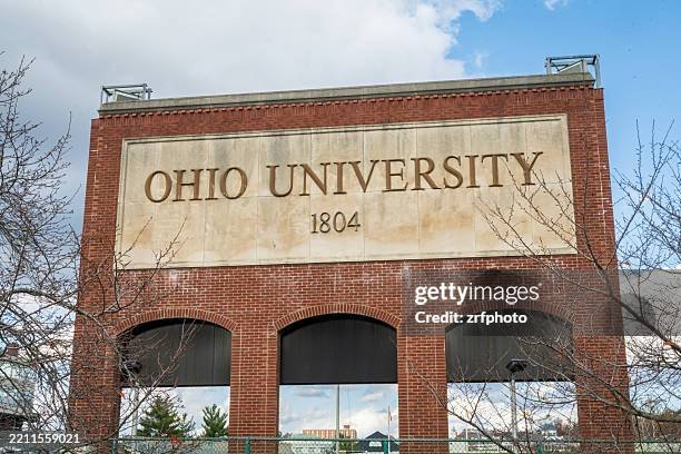 A large brick building with an inscription that reads 'Ohio University 1804' and three arched windows below the inscription, with some trees and a cloudy sky in the background.
