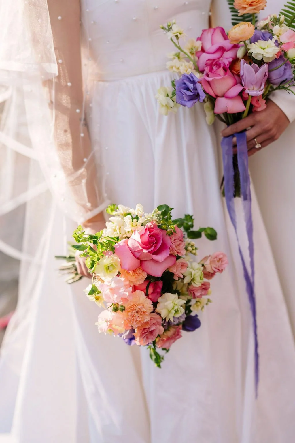 A bride and groom holding bouquets of pink, purple, and white flowers during a wedding ceremony.