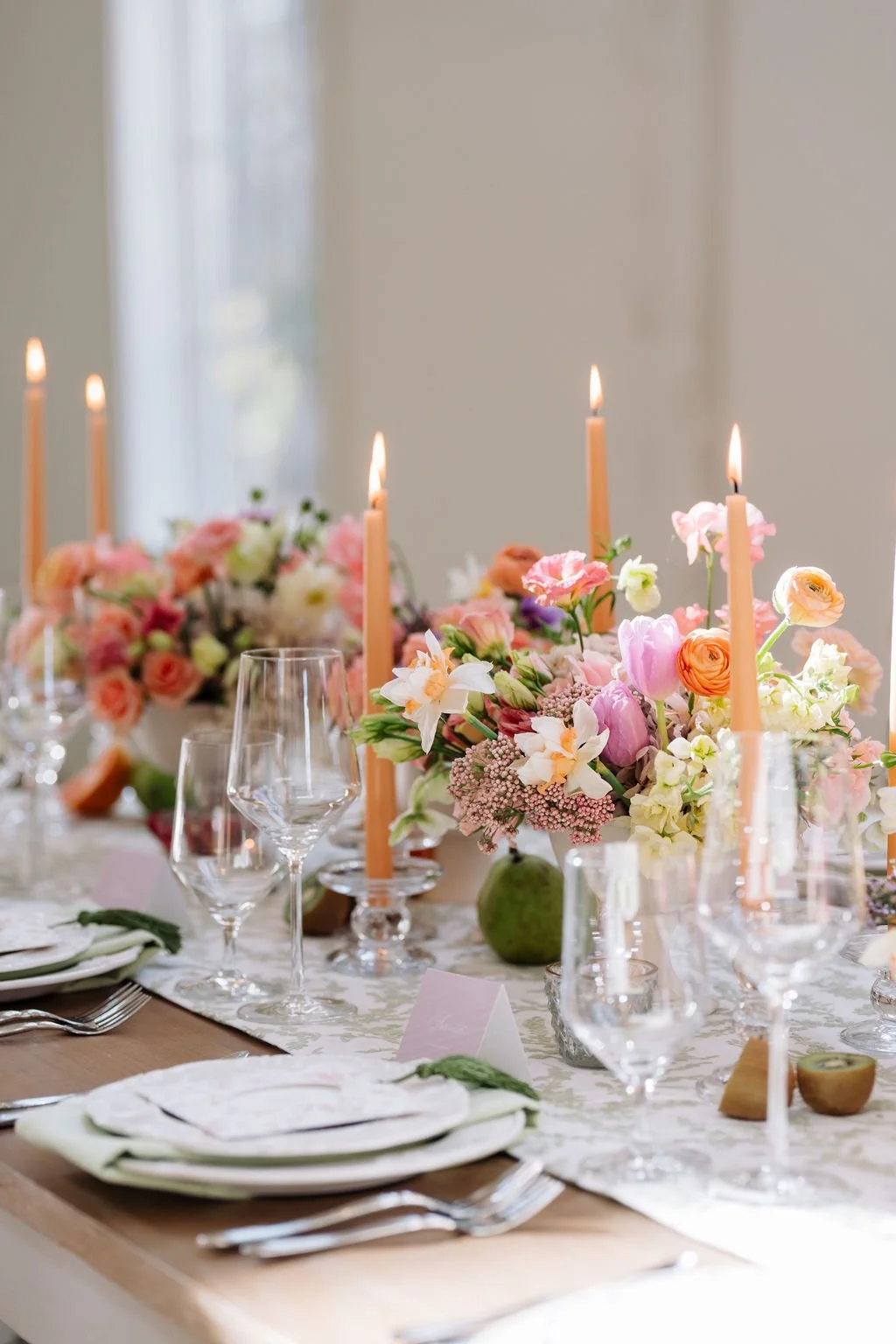 Elegant table setting with floral centerpieces, pink candles, and glassware for a formal event or celebration.