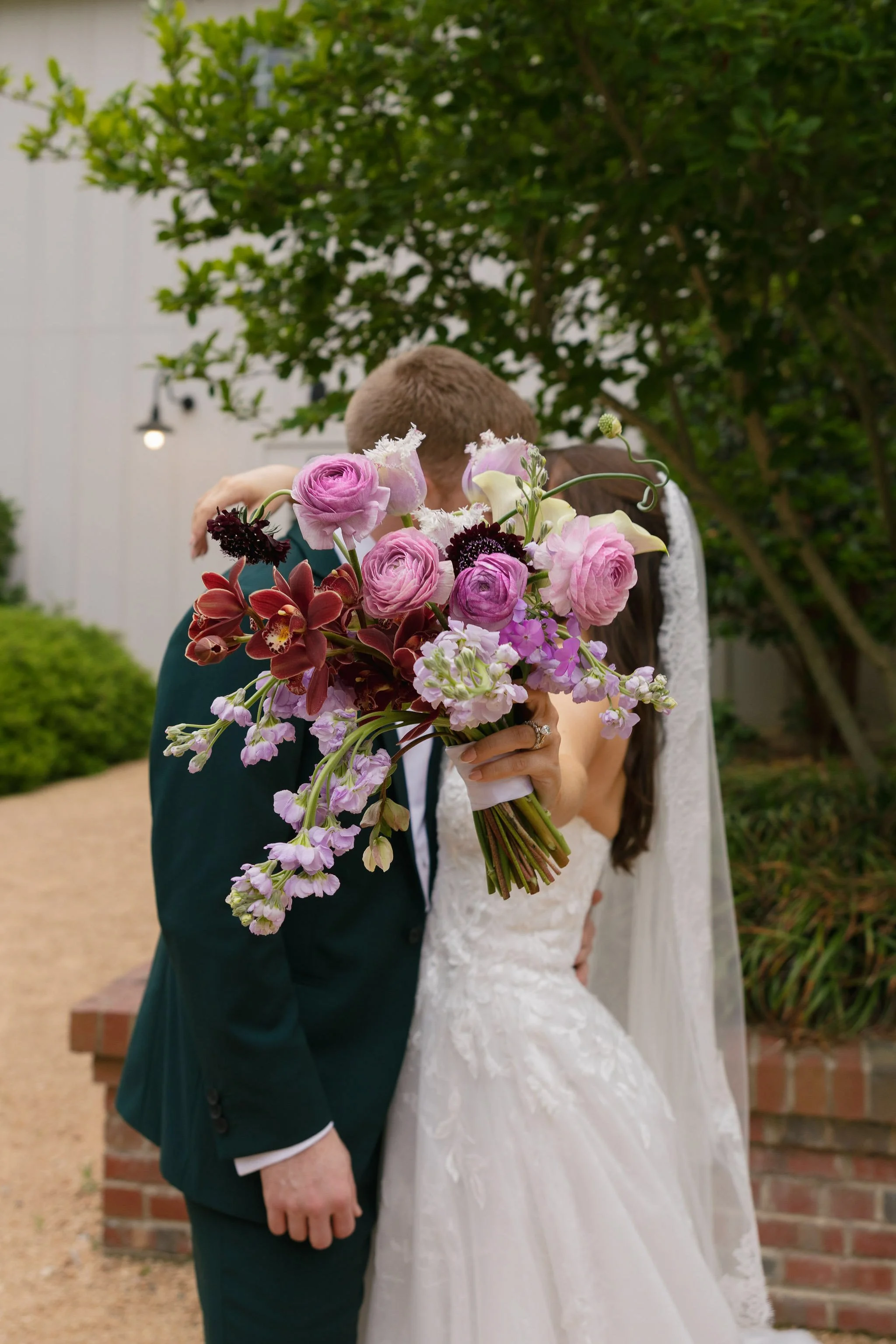 Modern flower-focused bridal bouquet of pink ranunculus, burgundy orchids and Picasso calla lilies 