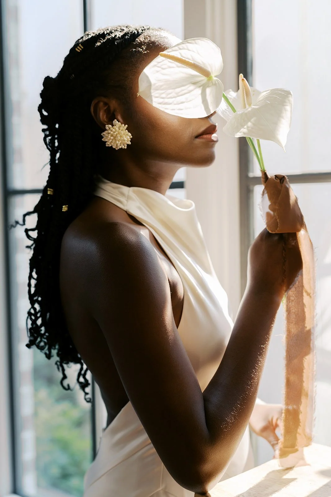  Editorial portrait holding a white anthurium with copper silk ribbon by a window, florals by Wild Flora 