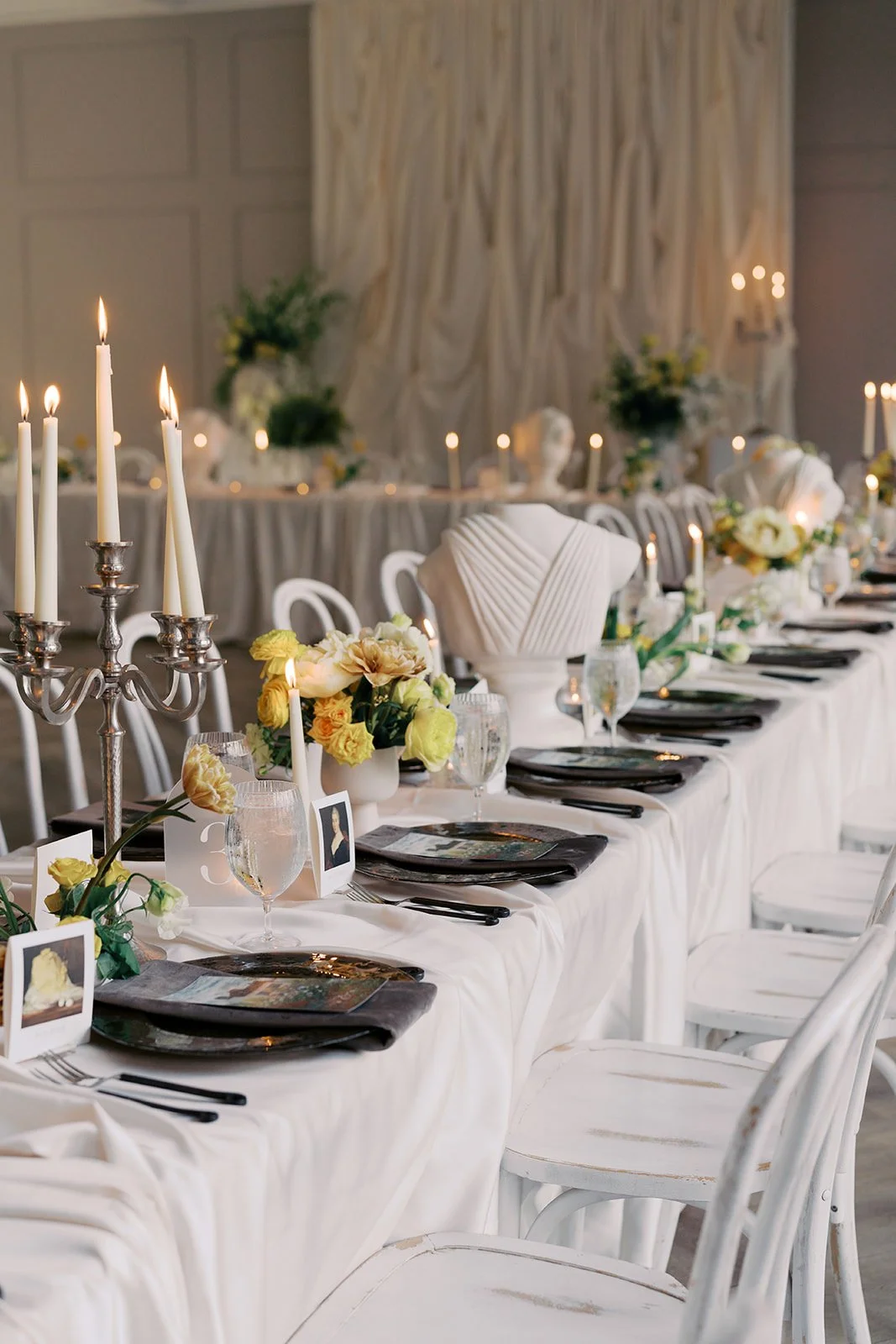  Candlelit editorial reception table with yellow garden rose centerpieces, a classical sculpture, and painterly menu cards at The Bradford 