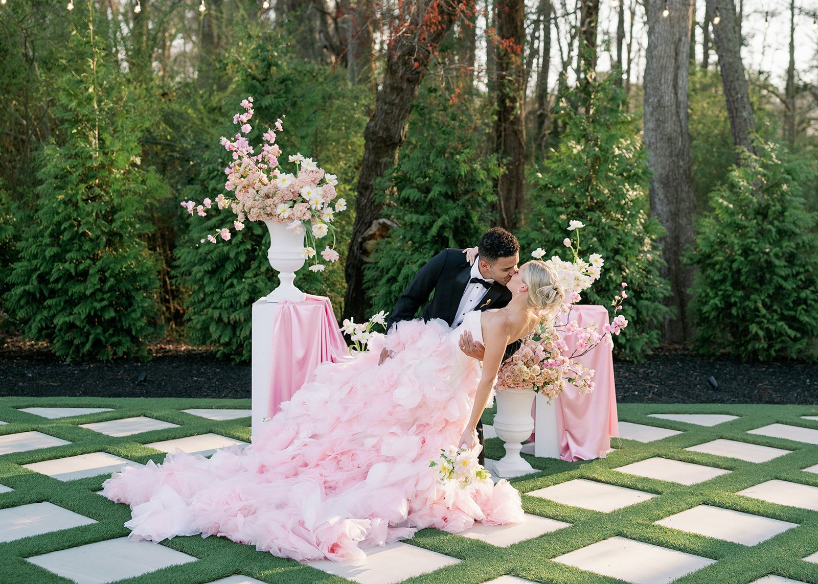 Couple Kissing In Front Of Styled Florals Outdoors.jpg