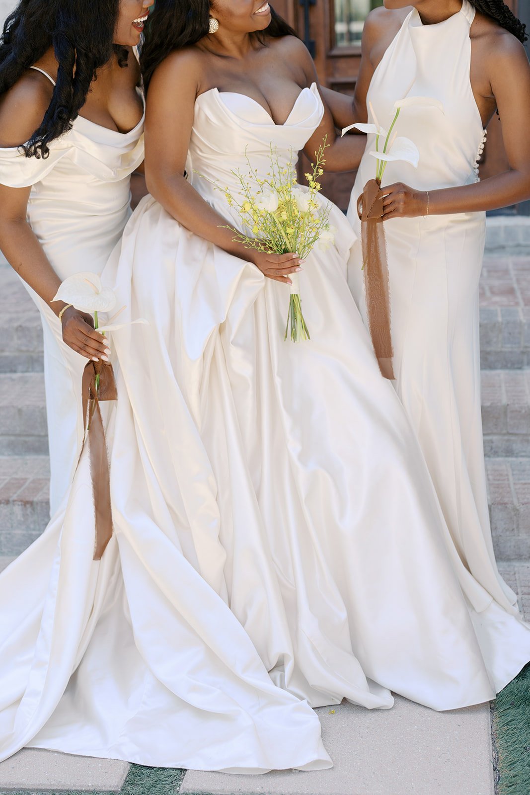 Bride holding a yellow oncidium orchid bouquet beside bridesmaids in ivory carrying single white anthurium stems with copper ribbon by Wild Flora