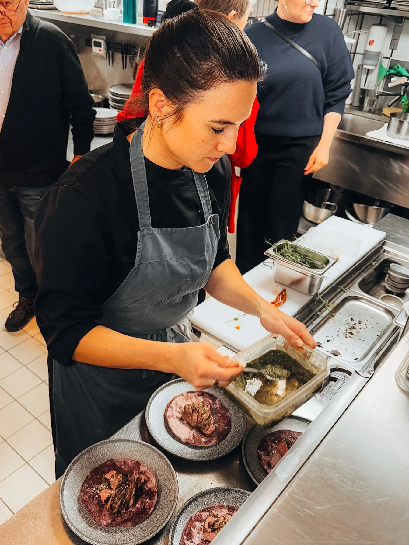 Eine Köchin bereitet Speisen in einer Küche vor, mit mehreren Tellern auf einem Tisch.