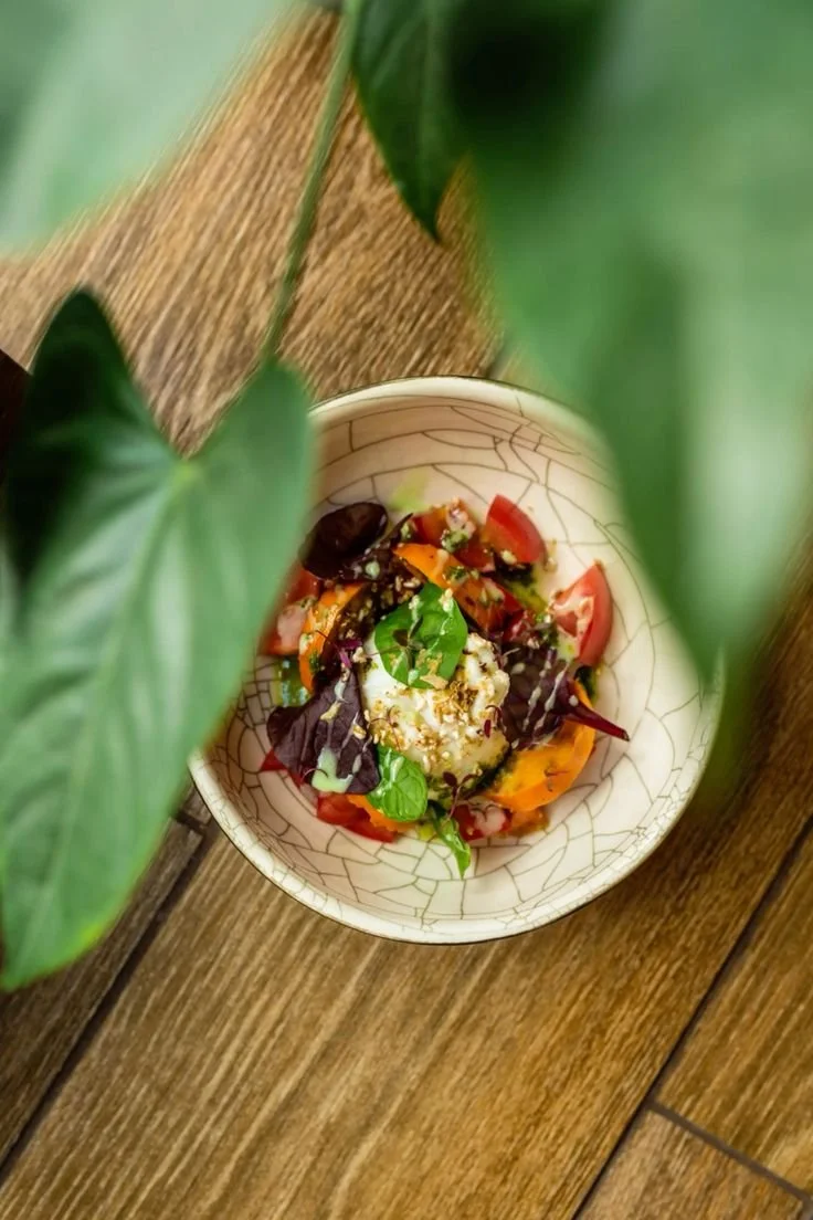 Salade colorée avec des tomates, de la laitue, du fromage et des légumes, vue du dessus à travers des feuilles vertes