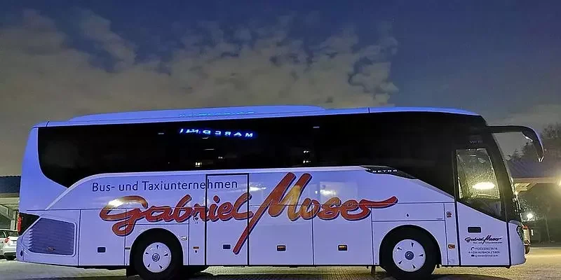 Bus mit Beschriftung 'Gabriel Mose' und 'Bus- und Taxiunternehmen' auf einer dunklen Straße bei Nacht