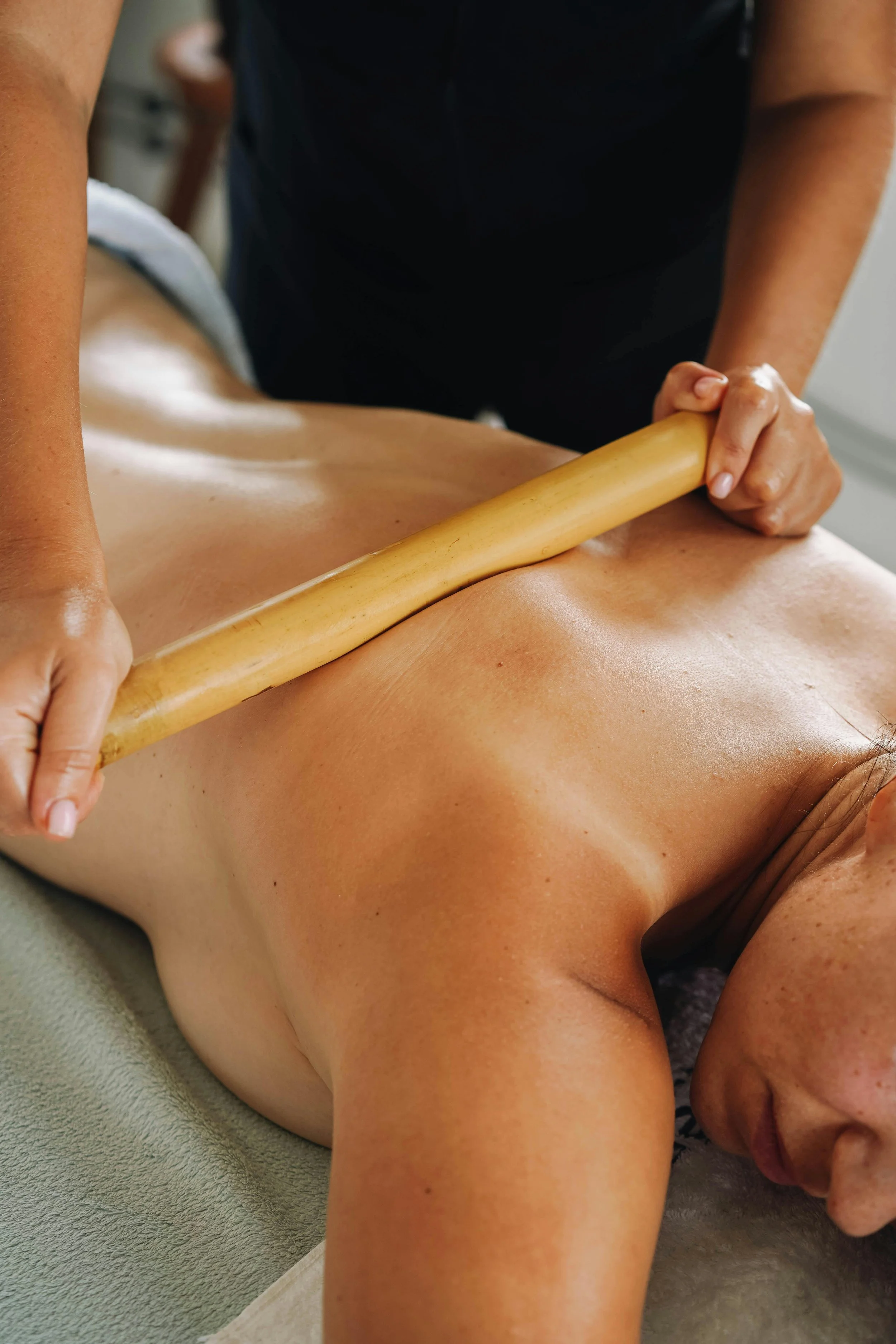 Person receiving a massage with a massage roller on their back in a wellness setting.