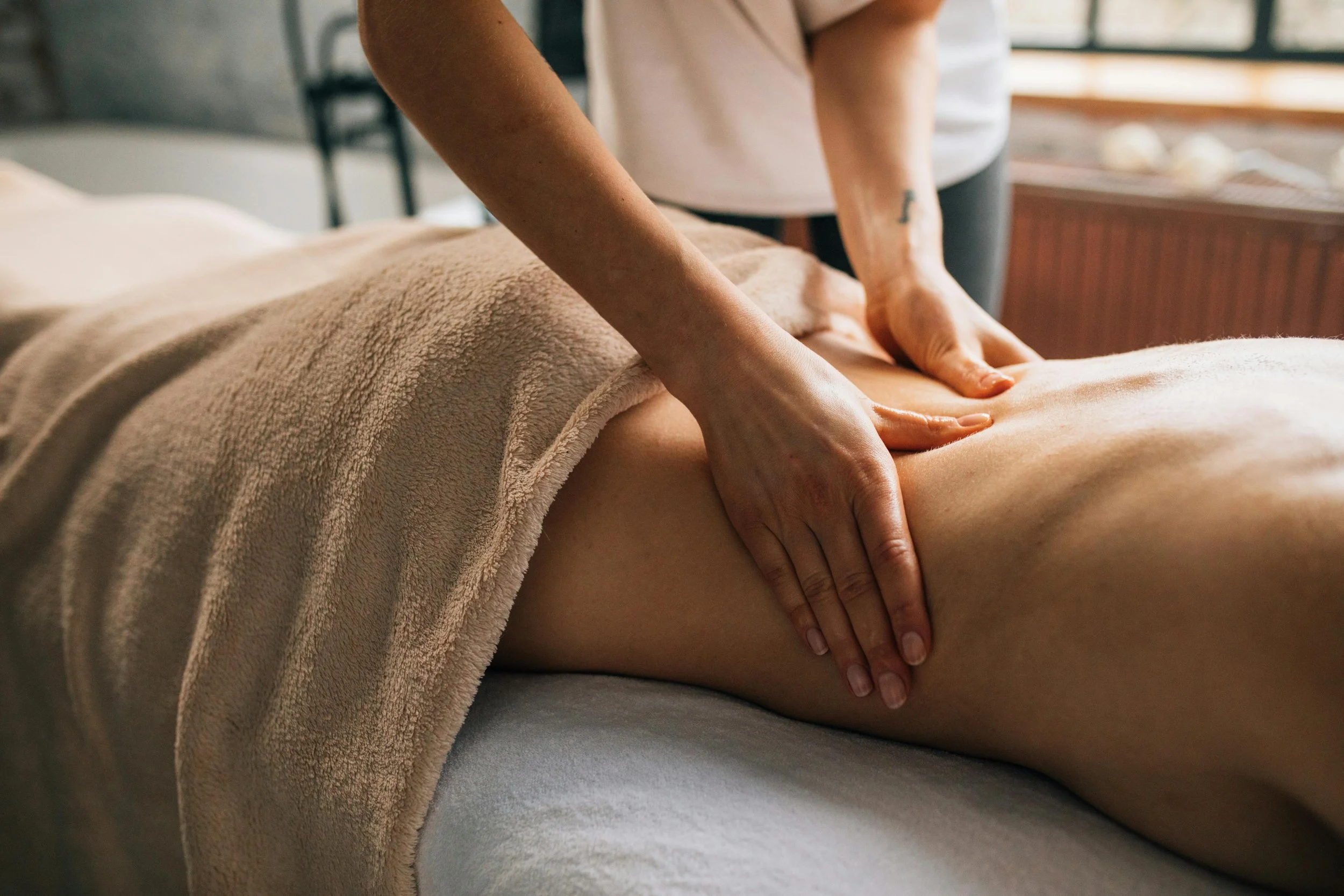 A person receiving a massage on their back from a massage therapist in a spa or massage therapy setting.