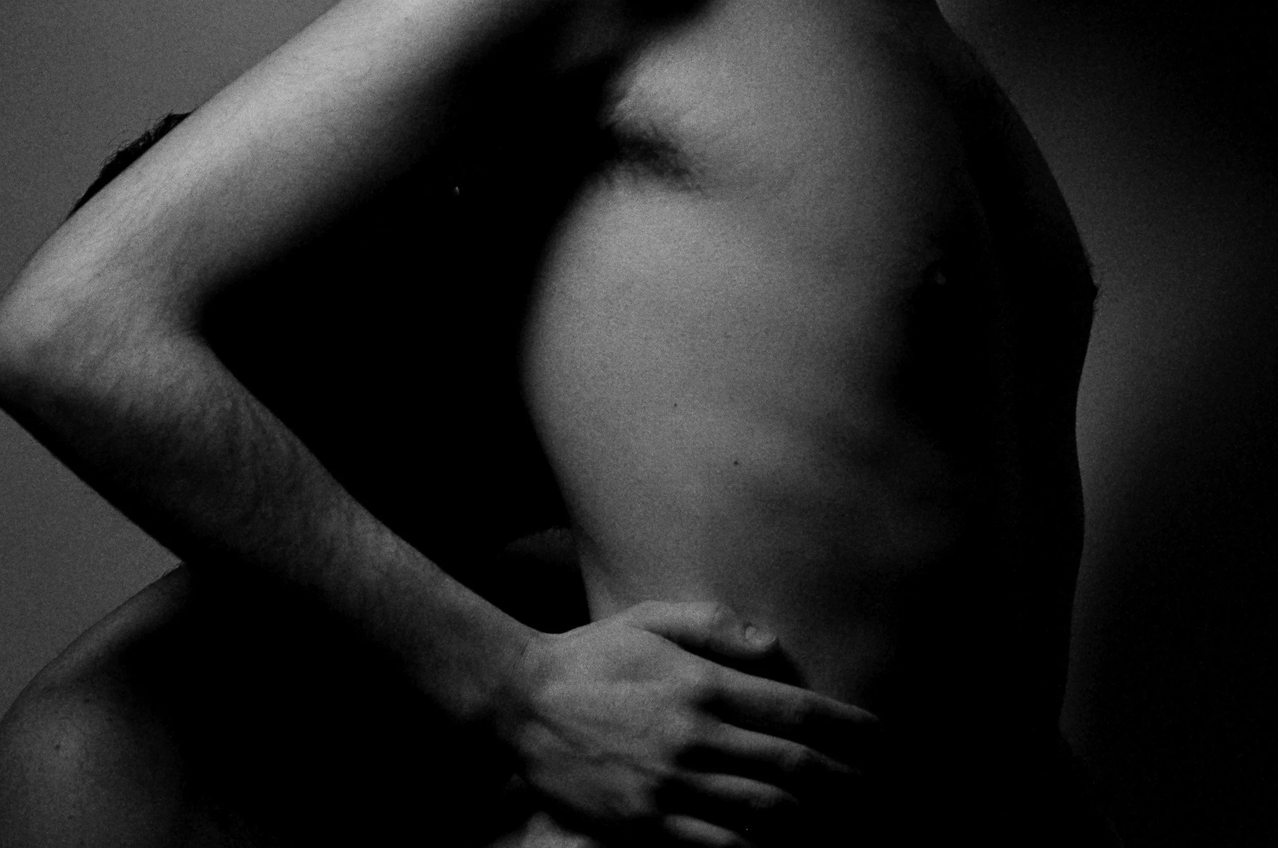 Black and white close-up of a person with dark hair, partially covering their face with their hand.