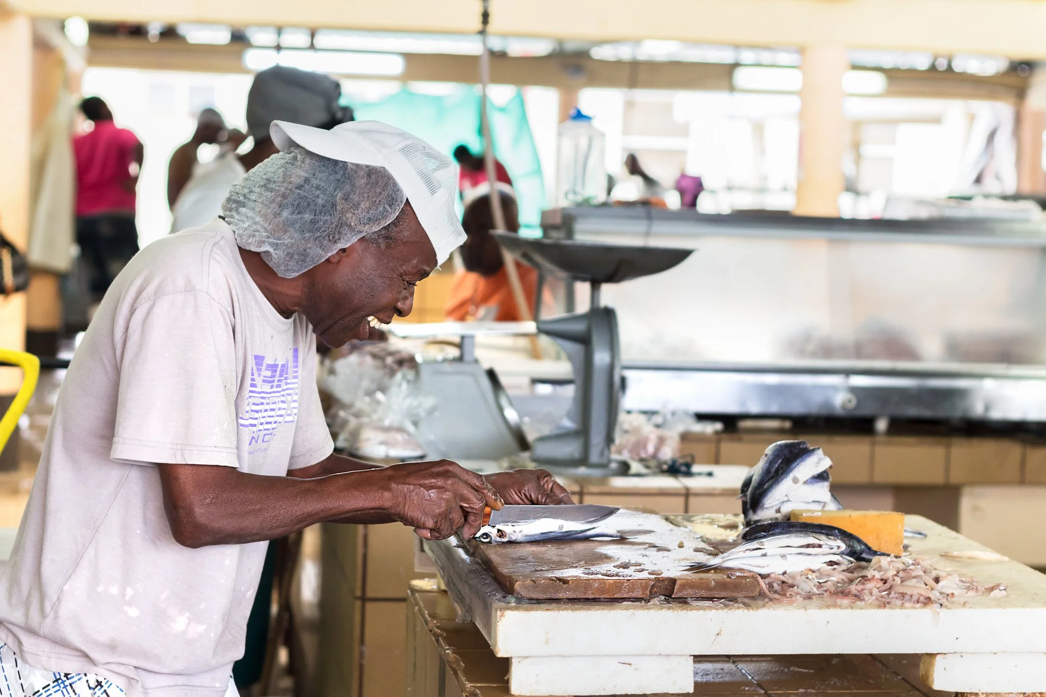 A male worker at the Bridgetown Fish Market is preparing flying fish for sale.