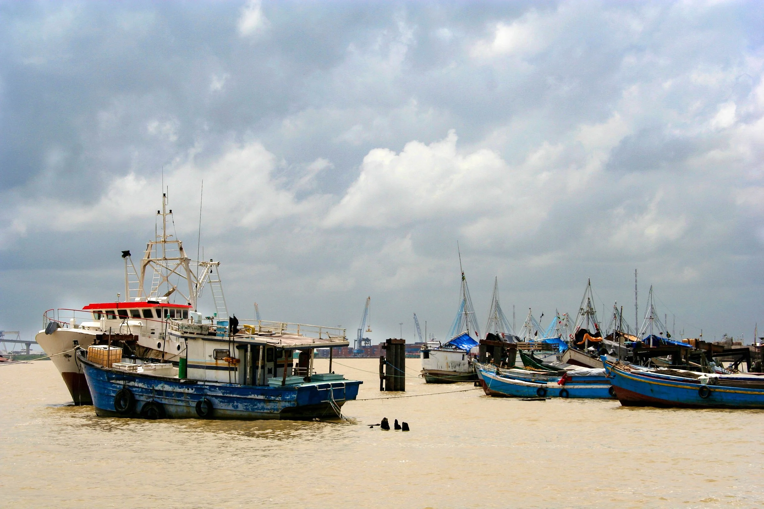 Boats docked at a harbor with cloudy sky overhead.