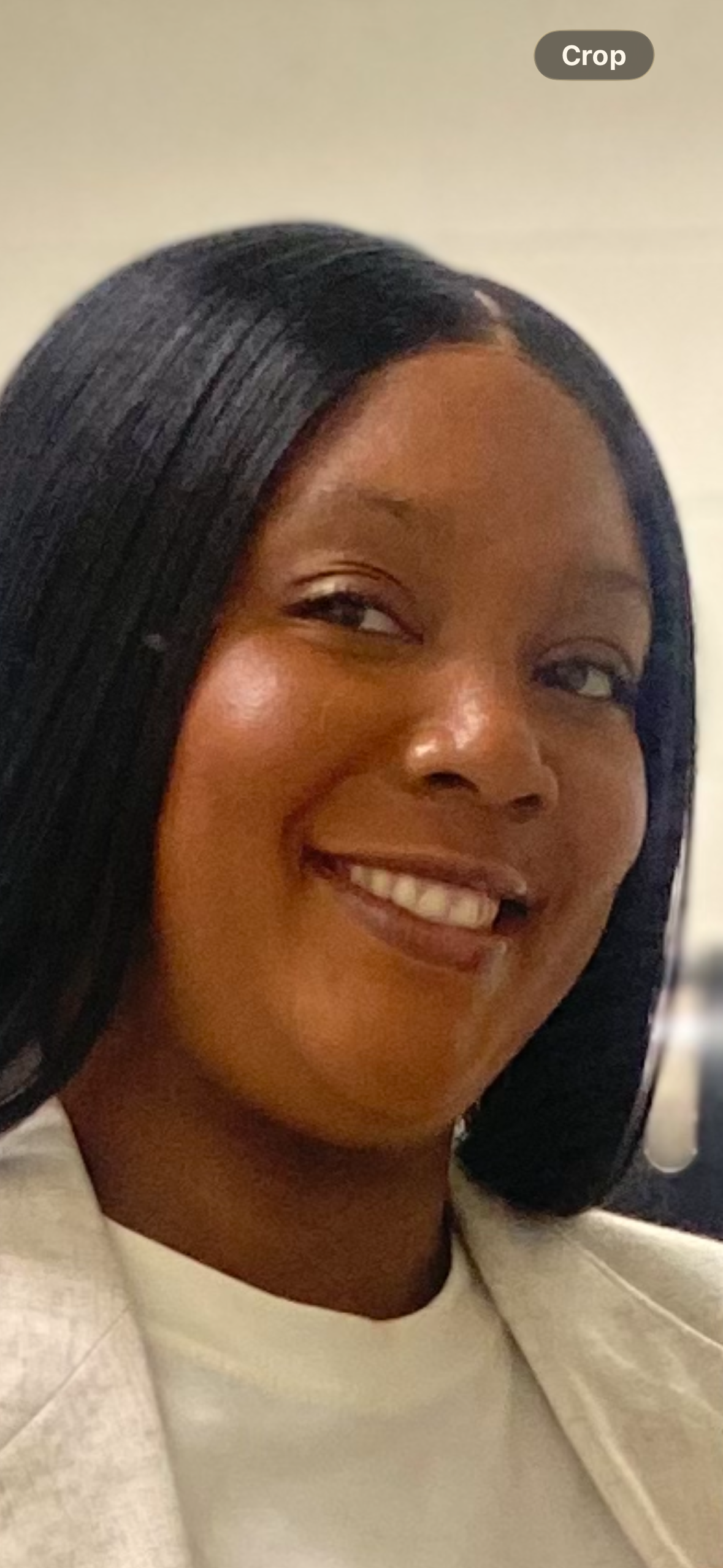A smiling woman with dark hair and smooth skin, looking slightly to the side, wearing a white jacket.