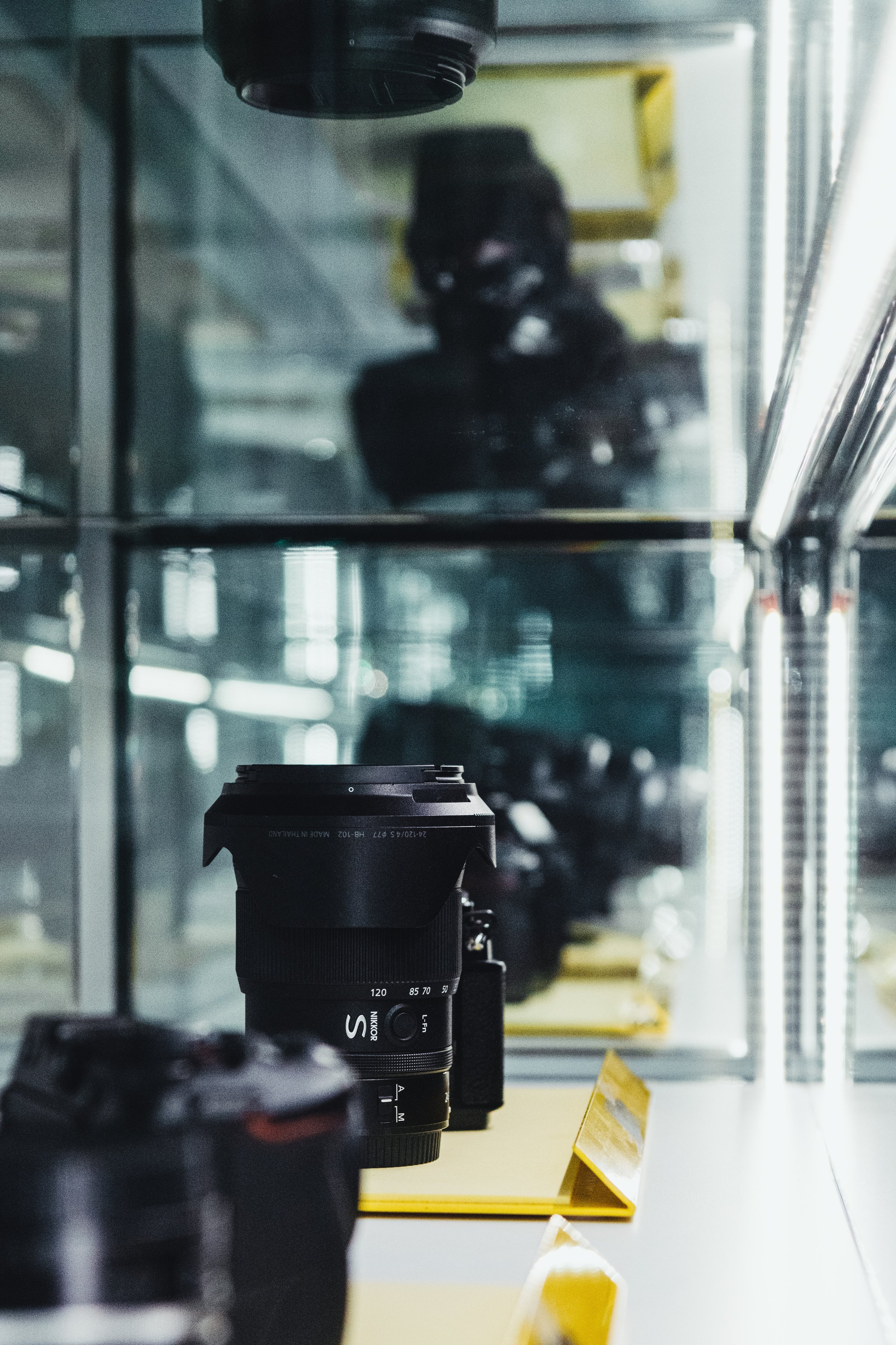 A camera on display behind a glass case at a museum or exhibit, with another camera in the foreground.