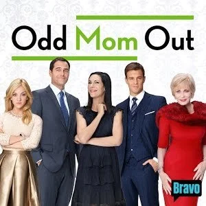Promotional poster for the TV show 'Odd Mom Out' featuring five well-dressed individuals standing together, with the show's title in large text at the top and the Bravo network logo in the lower right corner.