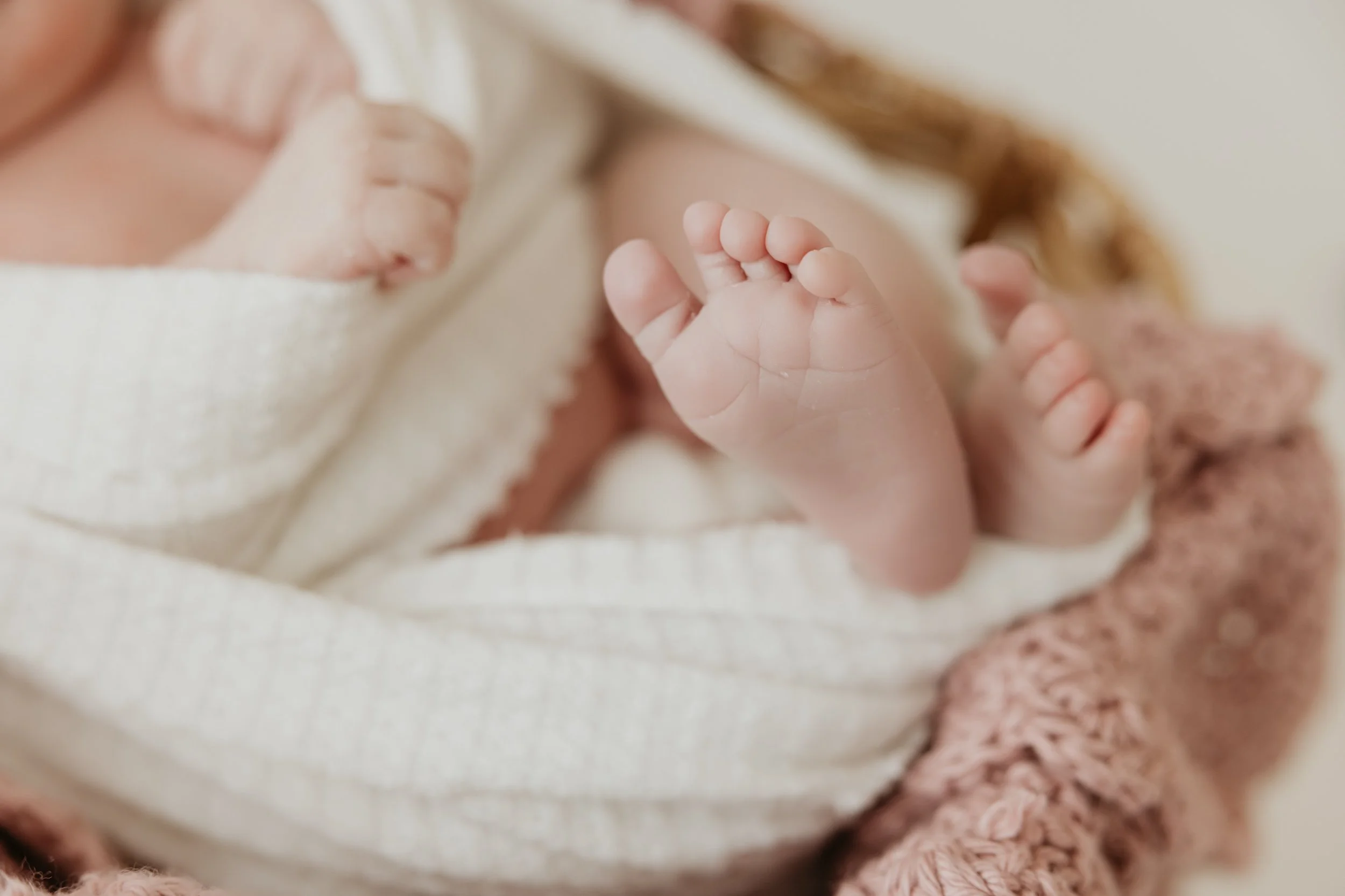 Close-up of a newborn baby's tiny feet wrapped in soft blankets.