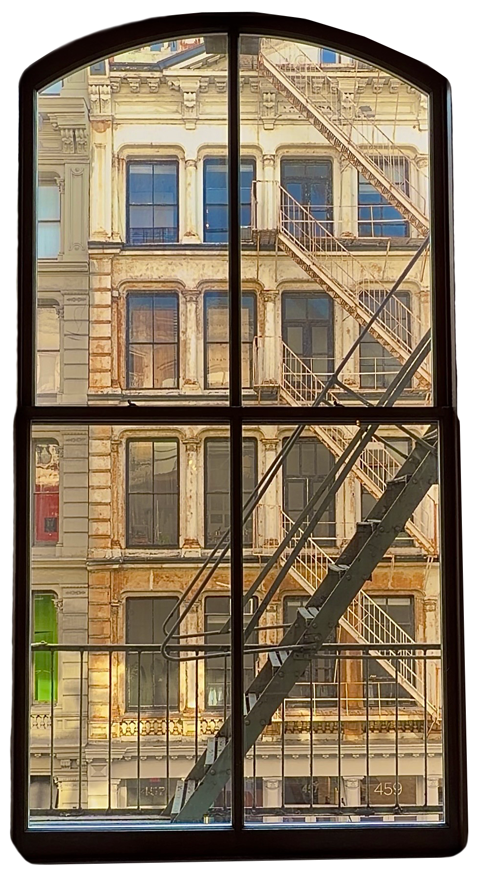 View of an old, weathered brick building with large windows and a fire escape outside the window.