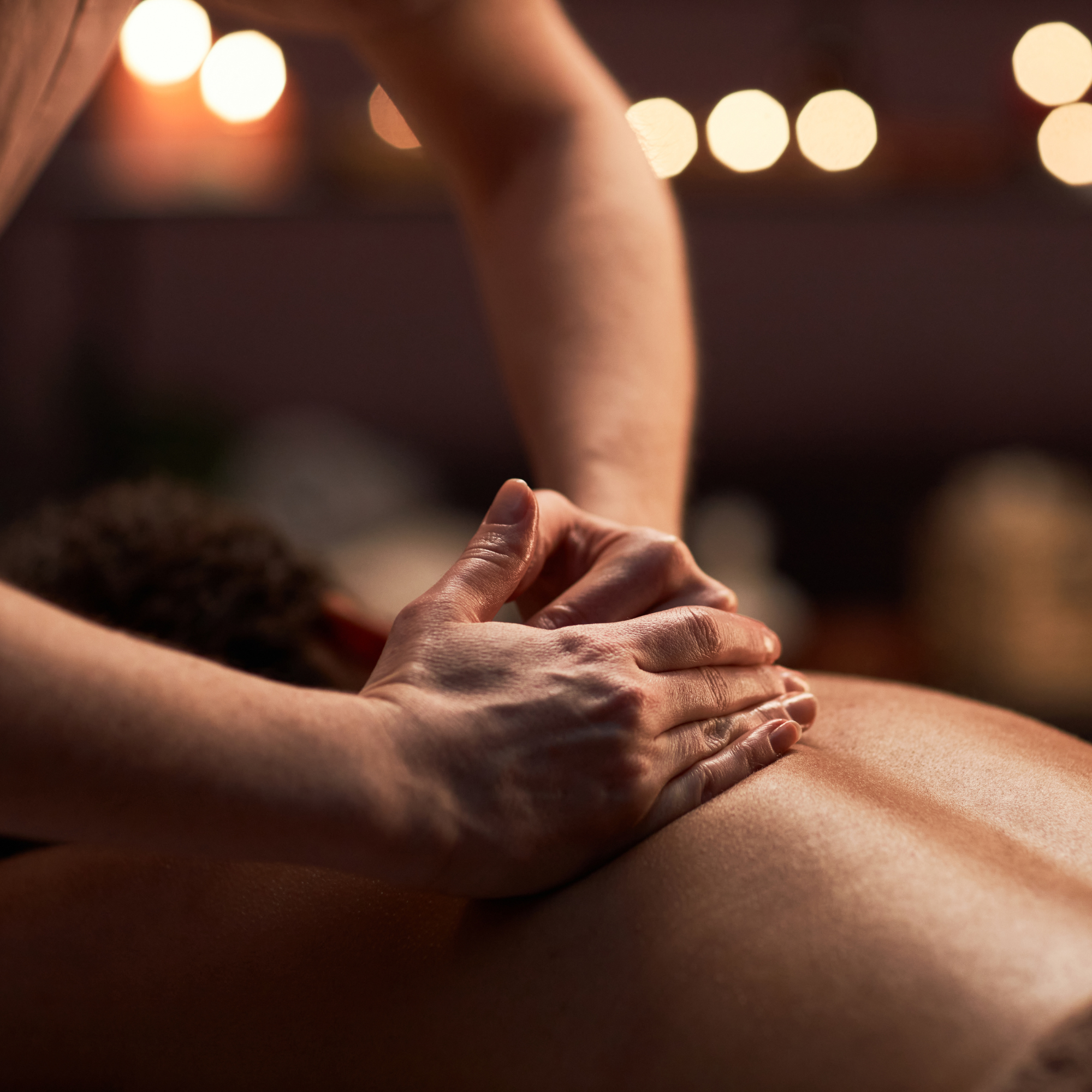 Close-up of a person receiving a massage, focusing on their back with a hand applying pressure.