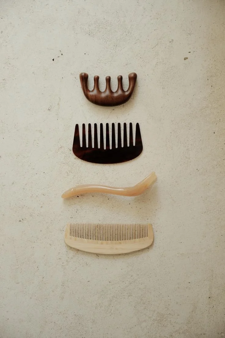 Four hair combs arranged vertically on a light-colored surface.