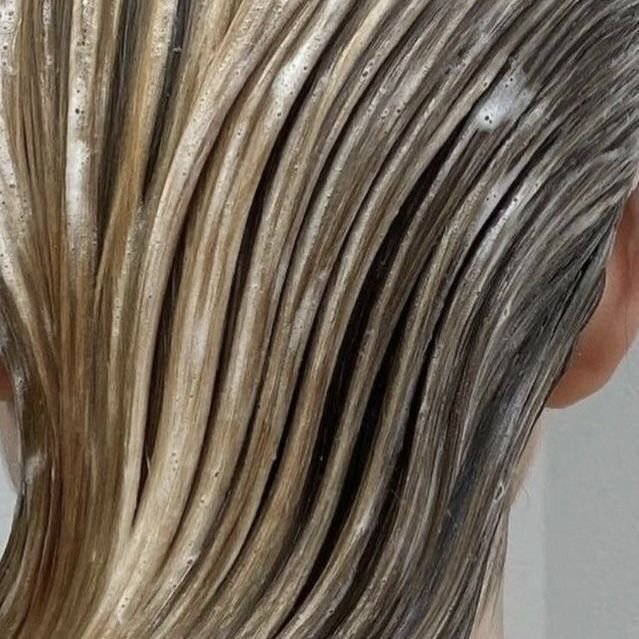 Close-up of wet, layered blonde hair with a background of a person's ear.