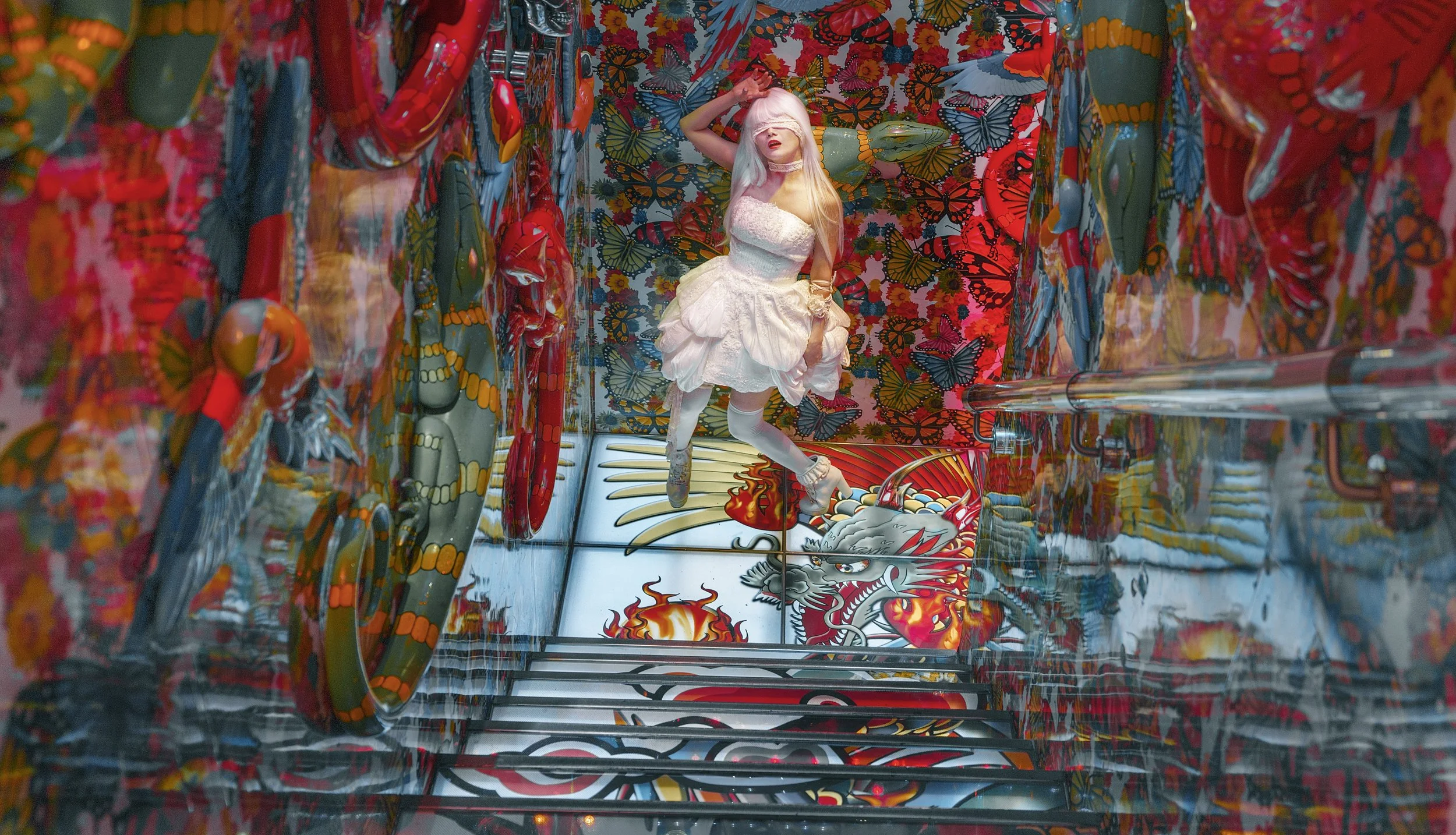 A woman in a white dress and tights is floating in a colorful, butterfly-themed room with dragon and butterfly decorations on the walls and floor.