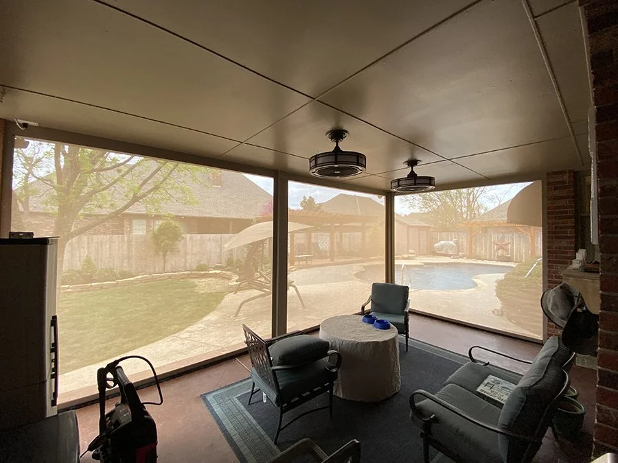 Room with mesh screens showing backyard with pool, patio, and trees.