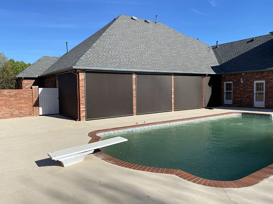Backyard swimming pool with a diving board and screened garage in a suburban home in clear weather.