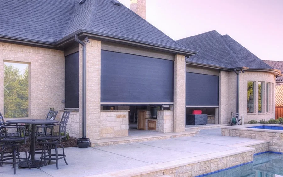 Back patio of a house with outdoor dining table, pool, and closed window shades