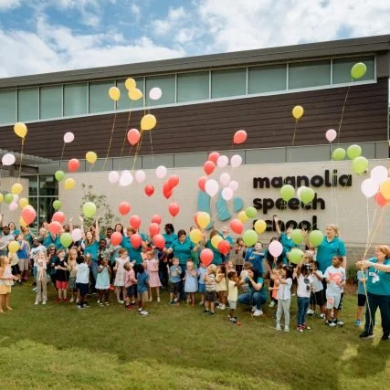 A group celebrates with multicolor balloons at Magnolia Speech School.