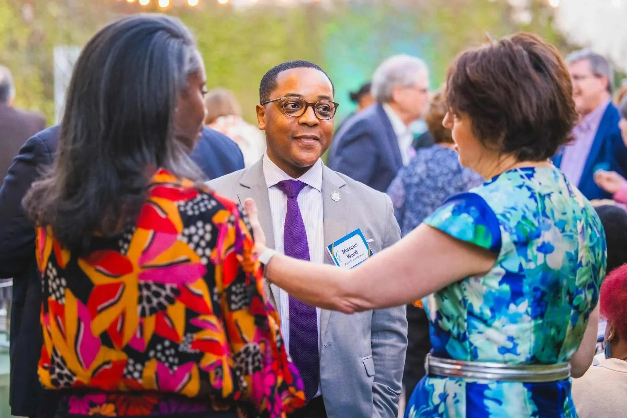 Two women and a man are engaged in conversation at CFM's Giving Forward event.