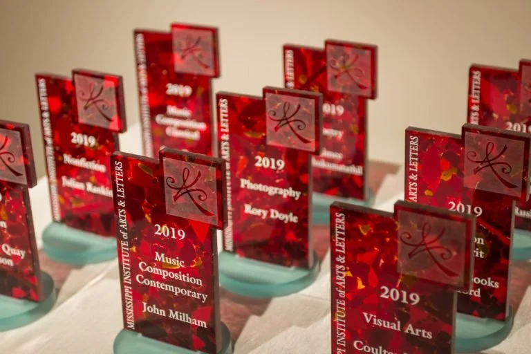 Red plaque awards for the 2019 Mississippi Institute of Arts & Letters Awards set up on a table