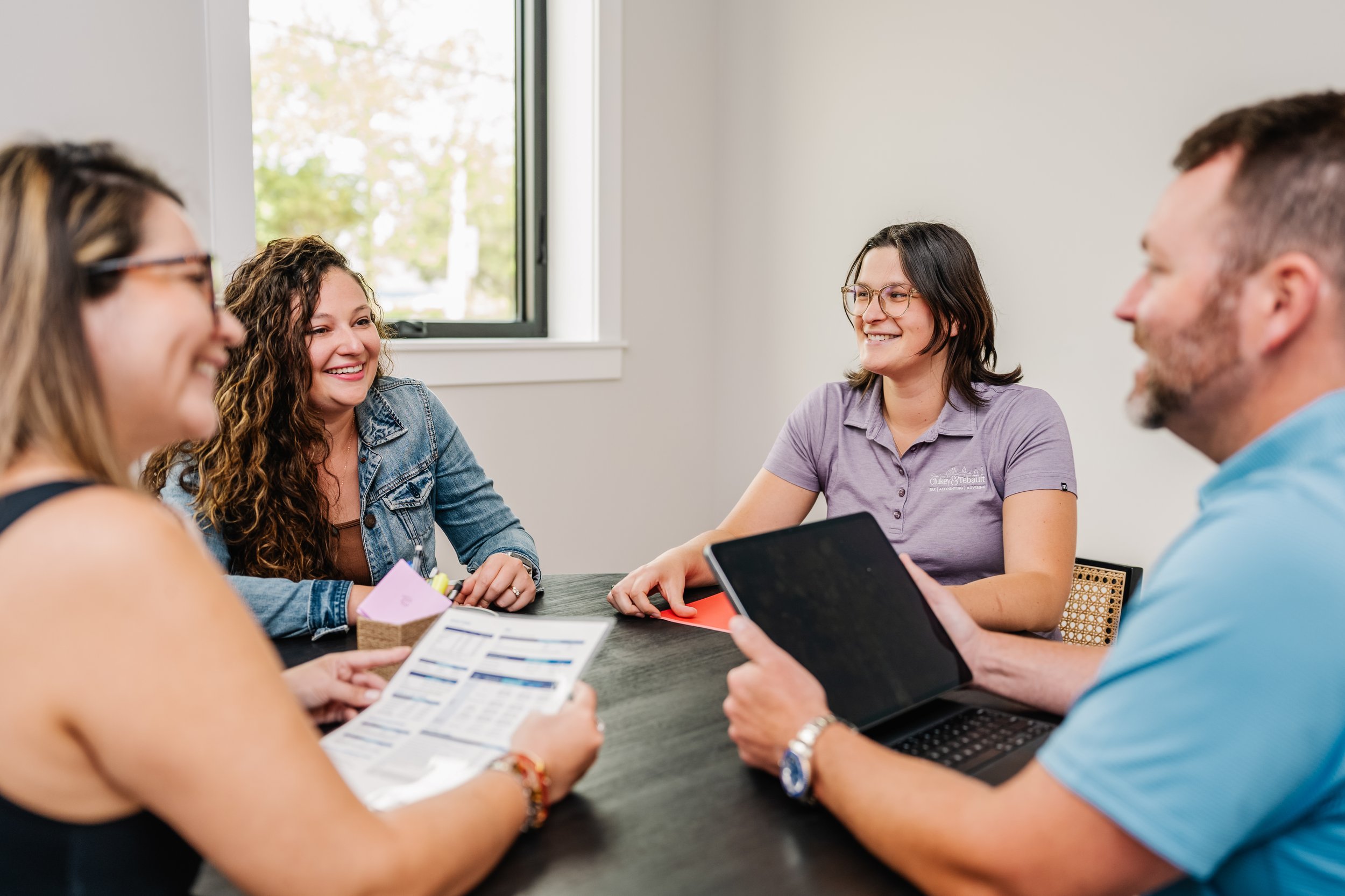 Clukey & Tebault's friendly staff meeting with a client around a table to discuss their tax information.