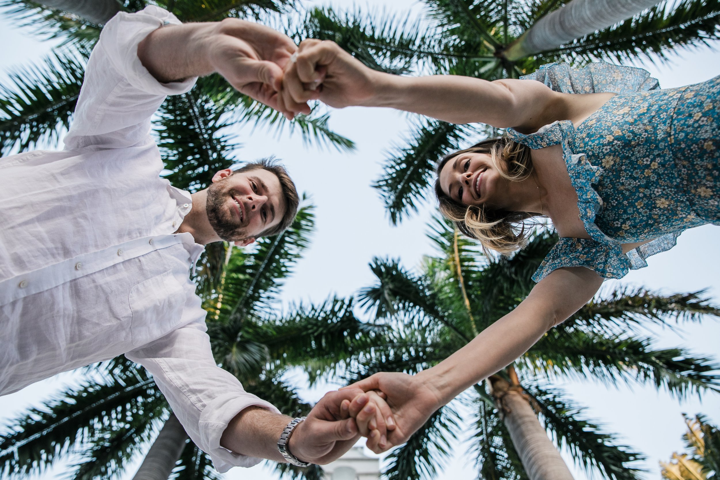 man and woman hold hands above photographer, palms in the background above their heads in Boca Grande
