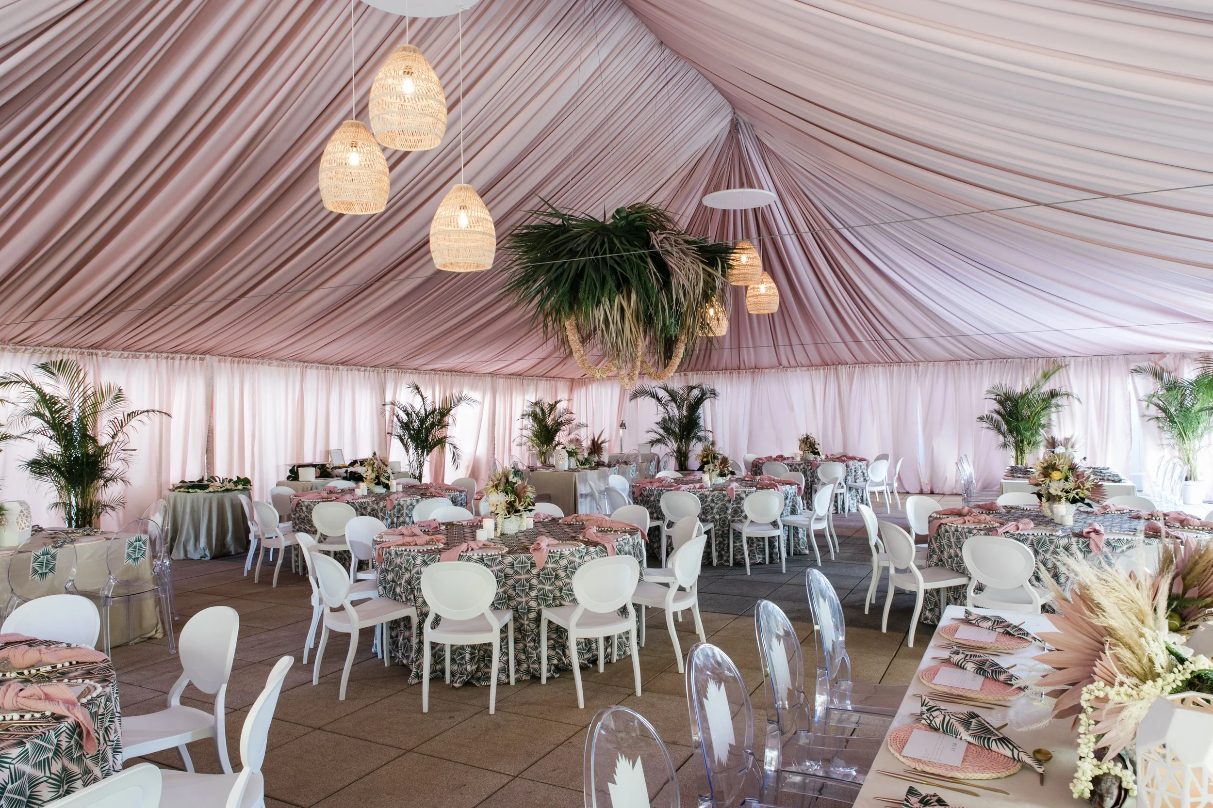 wide room view of a pink-draped tent with pink coastal decor on round and long tables. Decor by MMD Events and planning by RSBP Events.