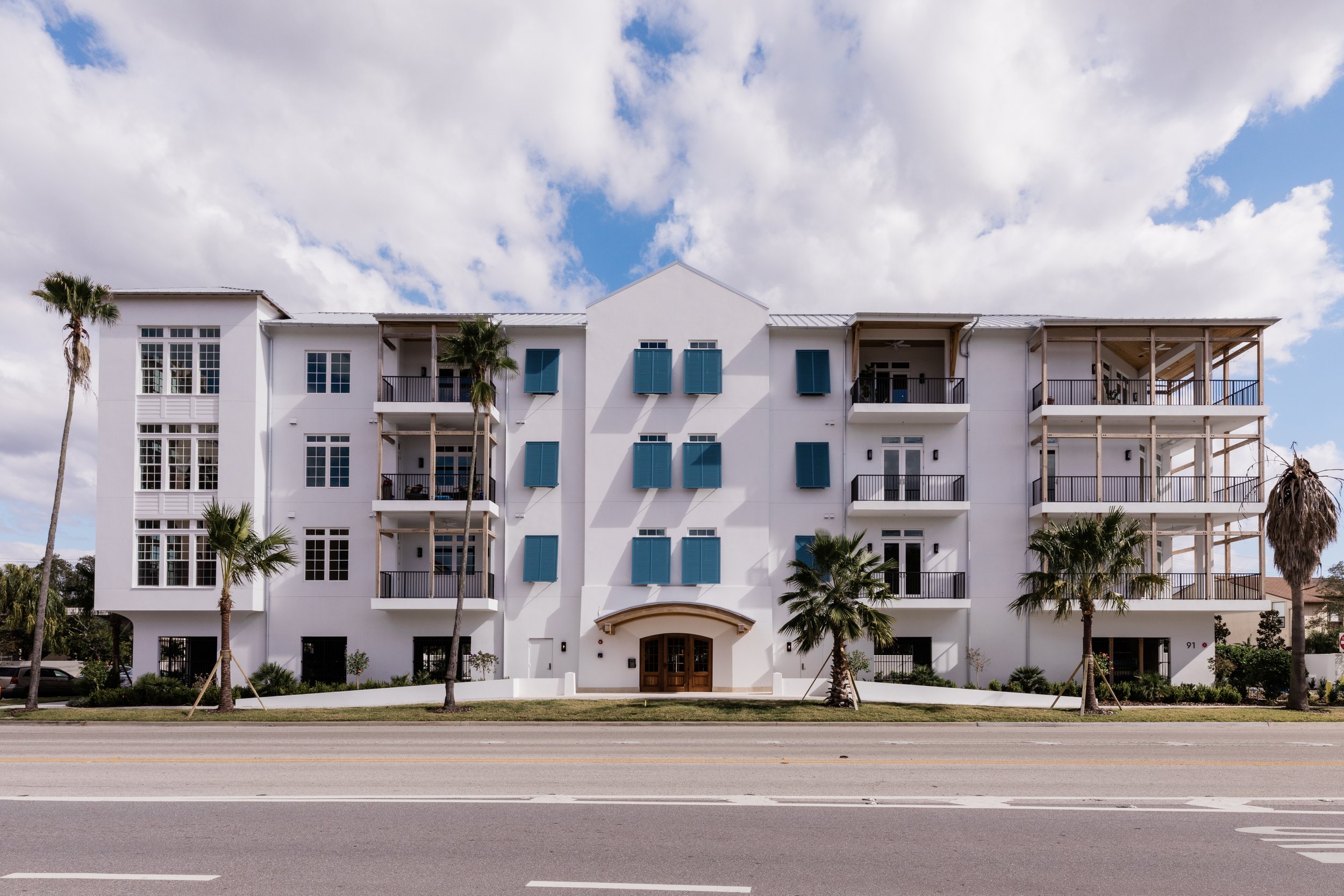 Mike Ruble architect designed the Islander condo on Davis Islands. Elevation view from the front. White building, blue shutters, wood railings.