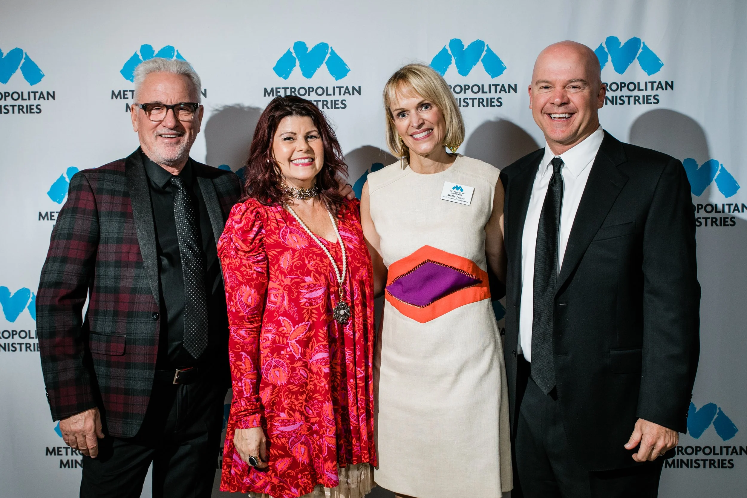 four people pose in front of a Step & Repeat at a Metropolitan Ministries fundraising event