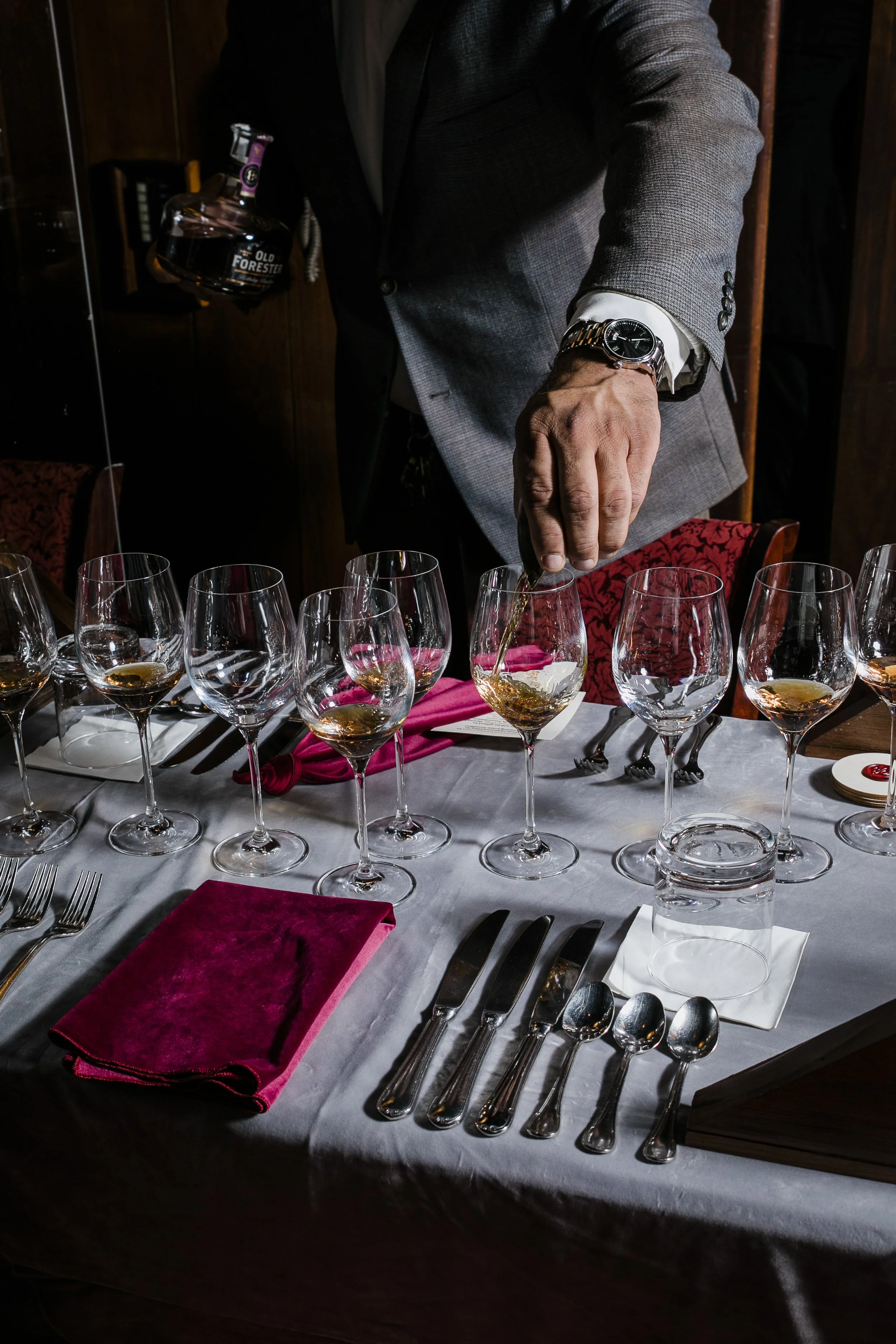 Man in suit pours whiskey into a glass at the Whiskey Tampa Foxtrot event